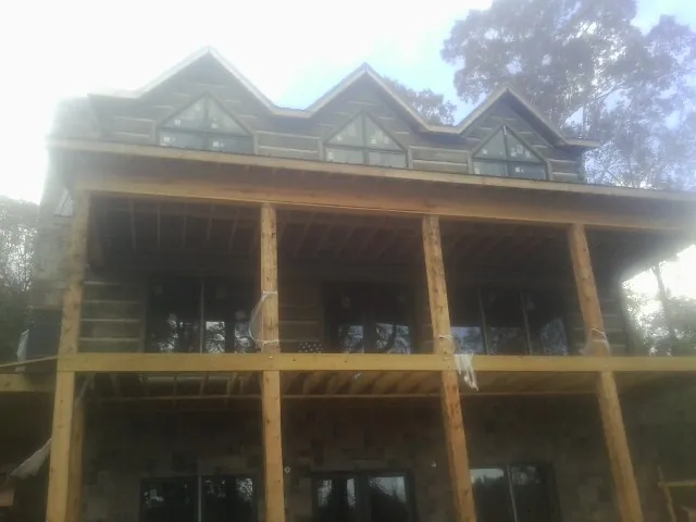 Dormers and porch framing on a large log home under construction — Roof Coating work by our crew in Ninety Six