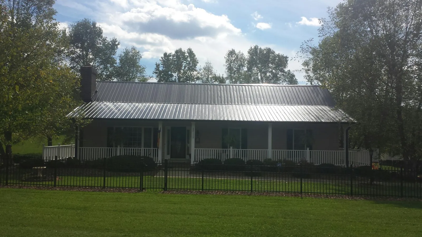 Gray metal roof on a brick ranch with a full width front porch — Gutter Guard Installation work by our crew in Ninety Six