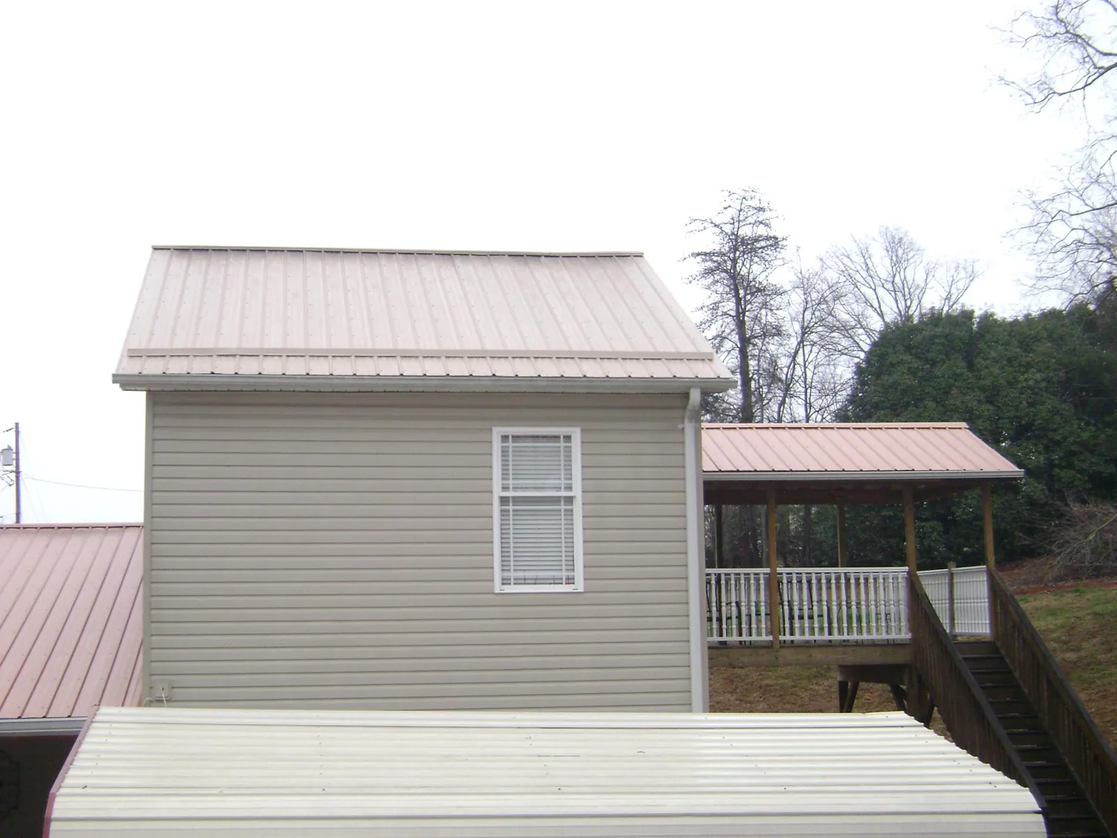 Tan metal roofs on a two story addition and attached porch, from a Roof Replacement job in Ninety Six