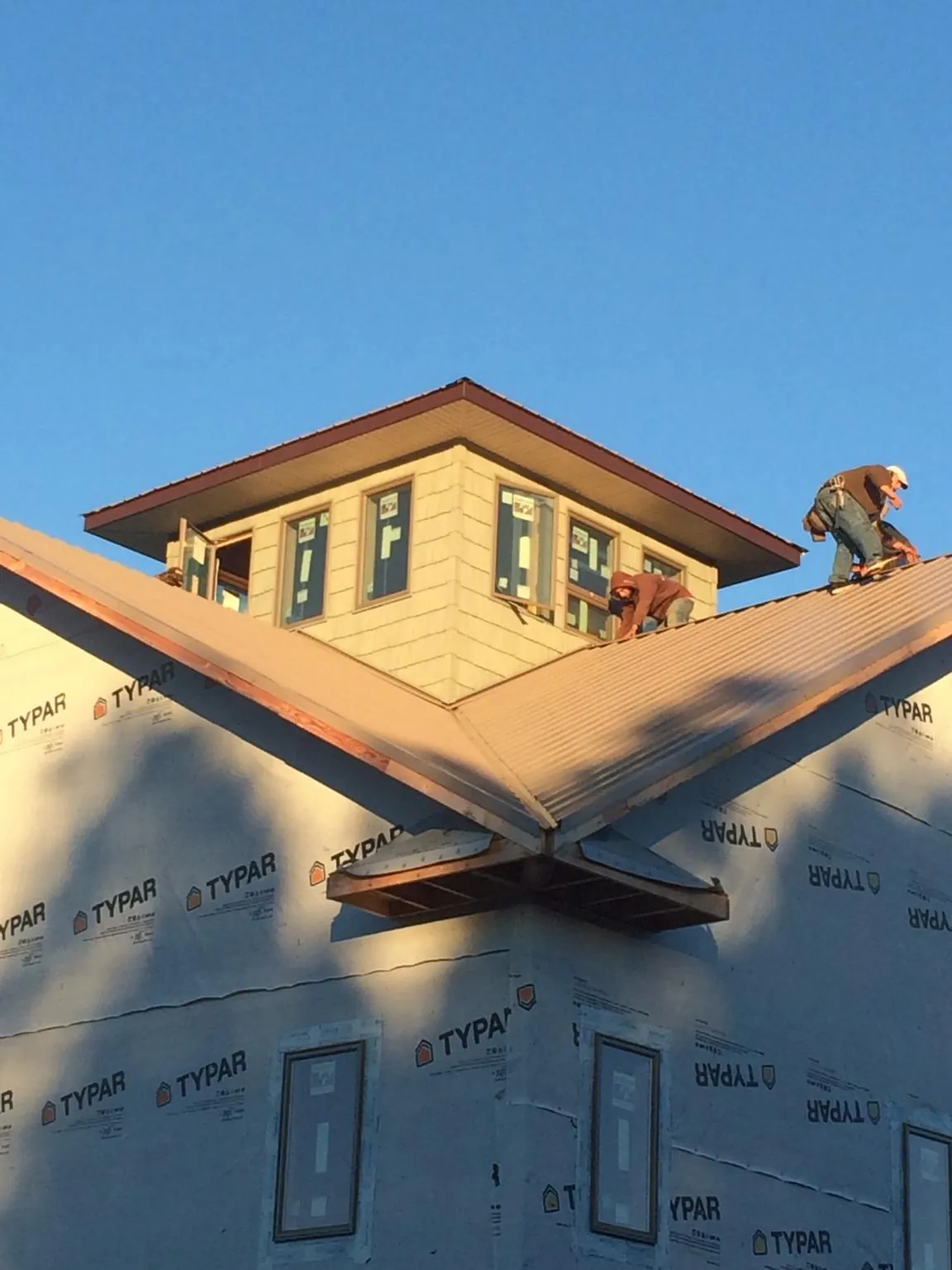 Roofers working around a rooftop cupola on a new metal roof at sunset — Roof Waterproofing in Ninety Six by Roofing Brothers
